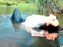 Chick in a sexy blouse takes a dip in the lake